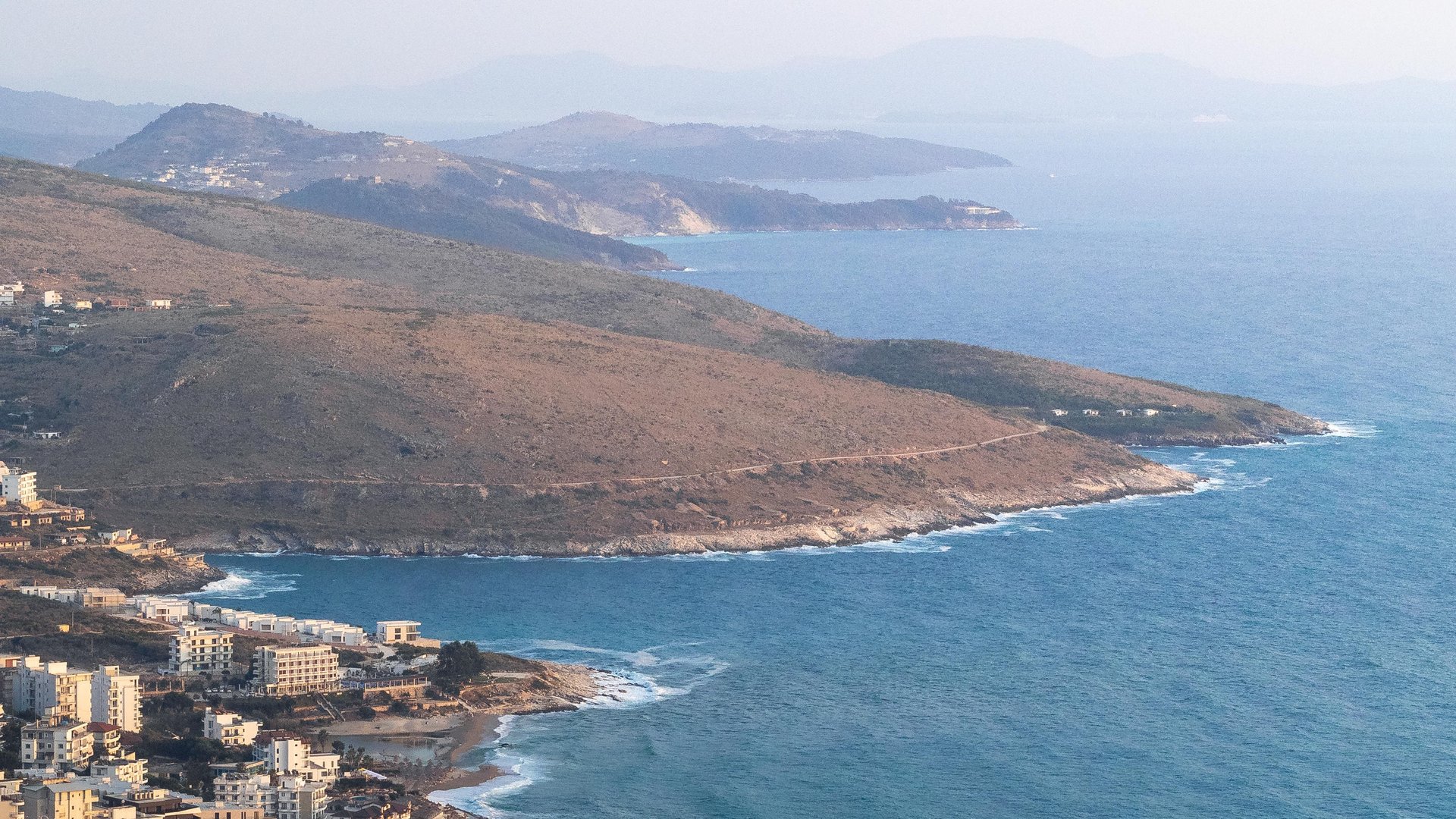 Coastal road above the turquoise Ionian sea on the Albanian Riviera at golden hour